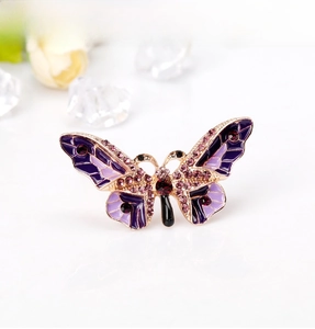 Detailed close-up of a purple enamel butterfly brooch with gold plating and pink crystals