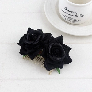 Detail of two black velvet fabric roses with gold metal teeth on a bridal hair comb