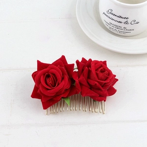 Detail of red velvet rose hair comb with golden metal teeth on a wooden surface