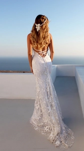 Detail of white lace wedding dress featuring cross strappy back and elegant fishtail train