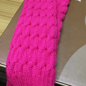 Detailed macro view of magenta thick cable knit texture on soft leg warmers