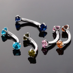 Close-up of curved eyebrow rings set with colorful zircon stones in stainless steel