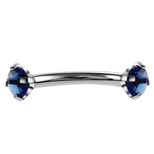 Detail of curved stainless steel eyebrow piercing with two dark blue zircon stones