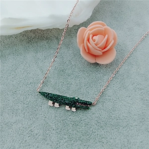 Détail du pendentif crocodile avec strass verts sur un collier en or rose élégant