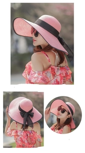 Dettaglio cappello di paglia rosa con fiocco nero e trama intrecciata naturale