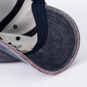 Detailed close-up of vintage washed denim baseball cap featuring distressed brim edges