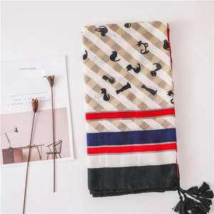 Détail d'un châle en coton et lin avec motif chat, quadrillage et glands noirs
