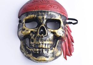 Detail of vintage pirate skull mask with golden texture and a red floral headscarf