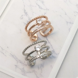 Close-up of triple-layered rose gold and silver rings with crystal accents on marble