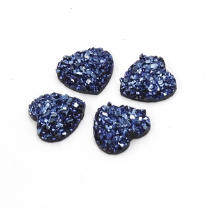 Detail van vier donkerblauwe hartvormige harsstenen met glittertextuur voor DIY-sieraden