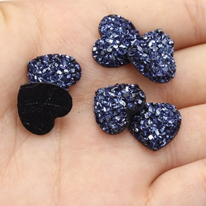 Macro-opname van 12mm blauwe hartvormige glitterstenen van hars in een handpalm