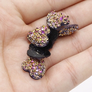 Macro-opname van hartvormige goudpaarse glitterhars cabochons in de hand voor DIY-knutselwerk