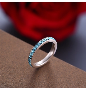 Macro shot of a slim stainless steel eternity ring featuring light blue channel-set crystals