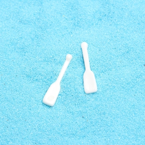 Detail of two white plastic miniature anchors for DIY phone case decoration on blue sand