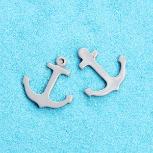 Macro view of two grey resin anchor charms on blue sand for DIY phone case crafts
