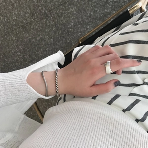 Close-up of minimalist 925 silver wide cross ring and textured snake chain bracelets
