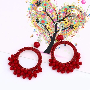 Detailed macro view of handmade red woven hoop earrings with faceted crystal beads