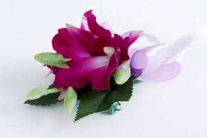 Primer plano de un prendedor de orquídea fucsia con pétalos de tela y cinta de raso