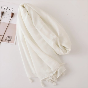 Detail of white cotton linen shawl featuring delicate fringe edges and breathable texture