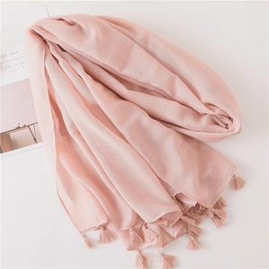 Close-up of soft light pink linen scarf with elegant tassel trim and natural texture