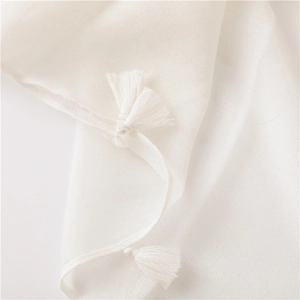 Detailed view of white cotton linen scarf featuring delicate fringes and glitter yarn