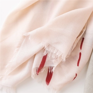 Detailed macro view of beige cotton linen scarf featuring red stripes and fringe tassels