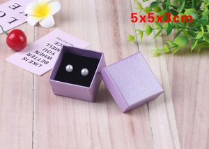Purple jewelry box sized 5x5x3cm showing pearl earrings on a wooden background