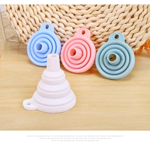 Macro view of four colorful folding silicone funnels in pastel shades on a wooden table