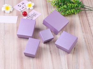 Flat lay of light purple jewelry boxes with pearlescent texture on a wooden table