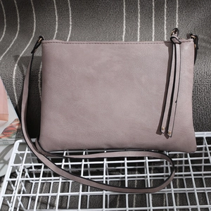 Detail of dusty pink PU leather envelope crossbody bag with decorative tassels