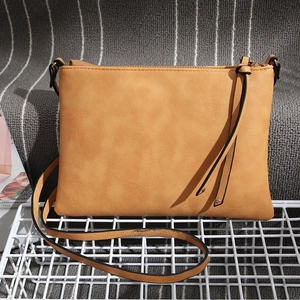 Detailed view of brown textured leather crossbody bag with tassel zipper on a mesh stand