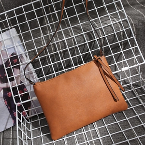 Brown faux leather crossbody envelope bag with tassel zipper detail in a metal basket