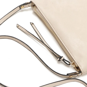 Detailed macro of beige envelope clutch with golden zipper and knotted leather tassels