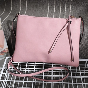 Detailed view of pink faux leather crossbody envelope bag on a white metal mesh rack