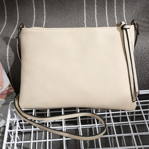 Detail of cream white faux leather crossbody bag with black trim and gold hardware