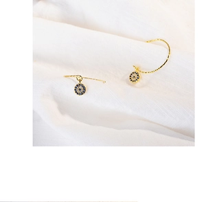 Macro shot of evil eye drop earrings with blue and white pavé crystals in gold setting