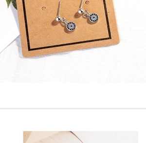 Close-up of silver Evil Eye earrings with blue and white crystals on a paper card