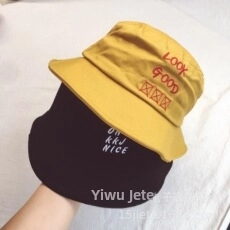 Detailed view of casual yellow and black bucket hats with embroidered graphic text