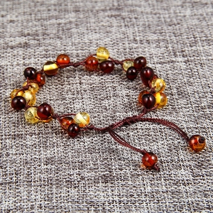 Handcrafted woven amber bead bracelet with multi-color stones on textured gray fabric