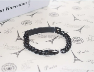 Macro detail of black Cuban link bracelet with a smooth rectangular metal ID tag