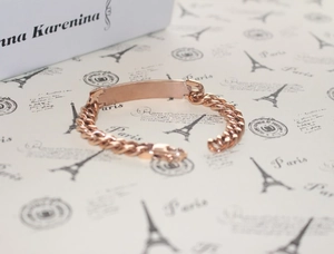 Macro shot of a rose gold titanium chain bracelet with a smooth rectangular nameplate