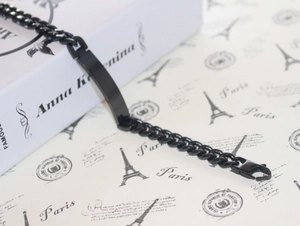 Macro shot of a black titanium steel ID bracelet lying on a book with a lobster clasp