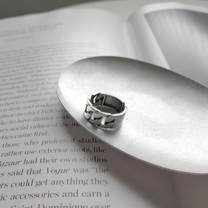 Detail of silver chain link ring placed on a metal tray over a fashion book page