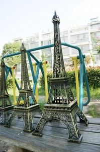 Tre modelli vintage della Torre Eiffel in metallo di diverse dimensioni su panca
