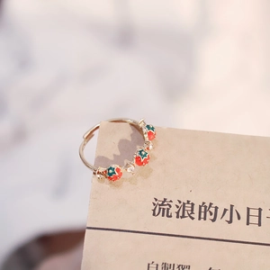 Macro detail of adjustable strawberry ring with red enamel and shimmering cubic zirconia