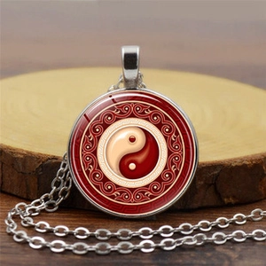 Close-up of mandala glass pendant featuring red and beige Yin Yang fish patterns