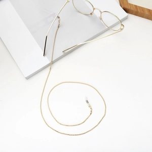 Close-up of golden box chain mask strap with silicone loops on a minimalist background