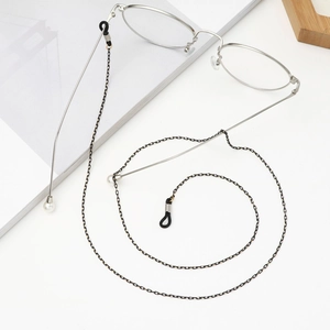 Macro detail of black metal eyeglass chain with white faux pearls and rubber loops
