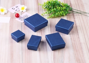 Macro shot of dark blue textured jewelry boxes for rings and necklaces on wood background