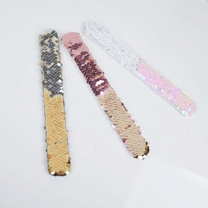 Macro detail of three reversible sequin slap bracelets showing color-changing flip texture
